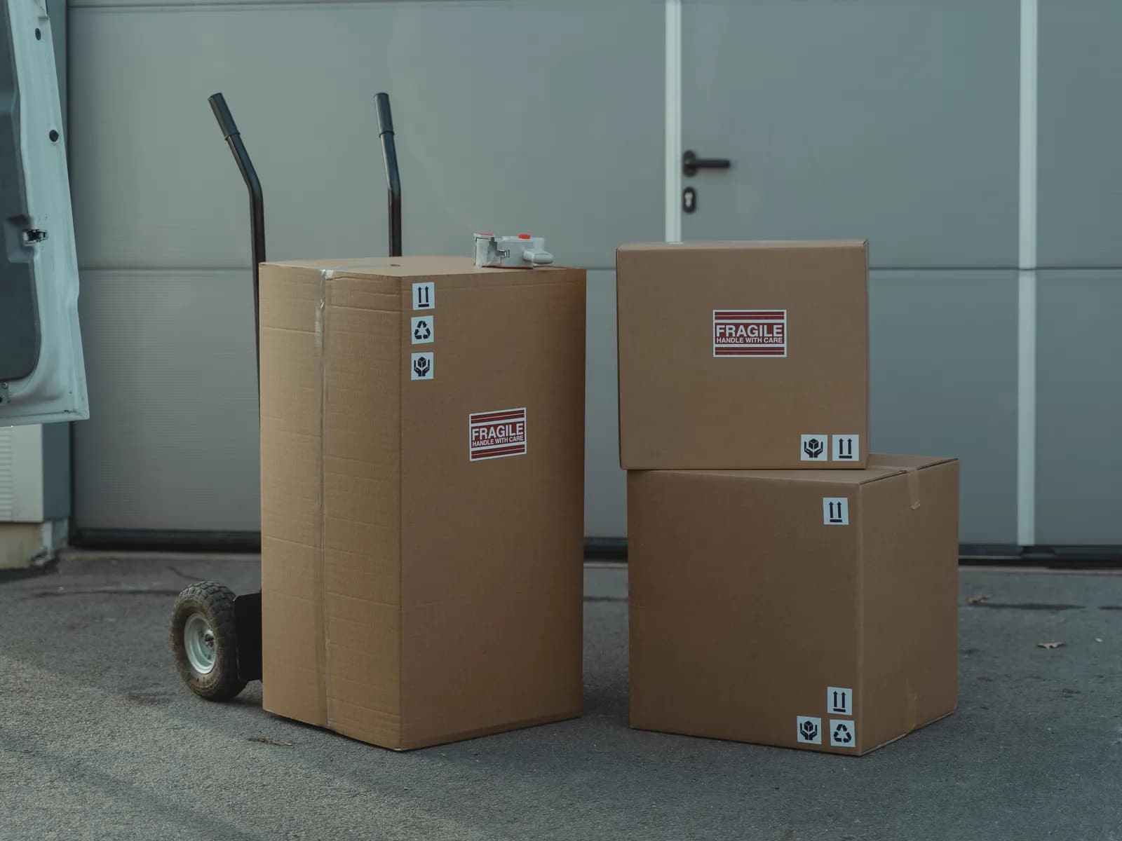 Packed cardboard boxes and a hand truck staged by a loading door